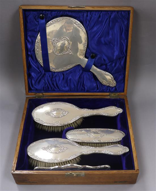 A cased George V repousse silver five piece dressing table set, Chester, 1912.